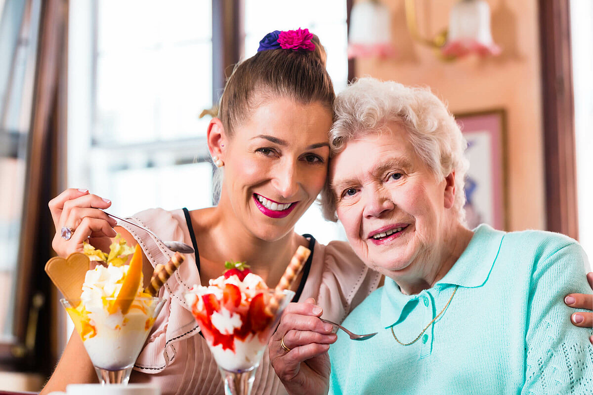 Seniorin mit Angehöriger essen Eis bei der Eisflatrate im Alloheim