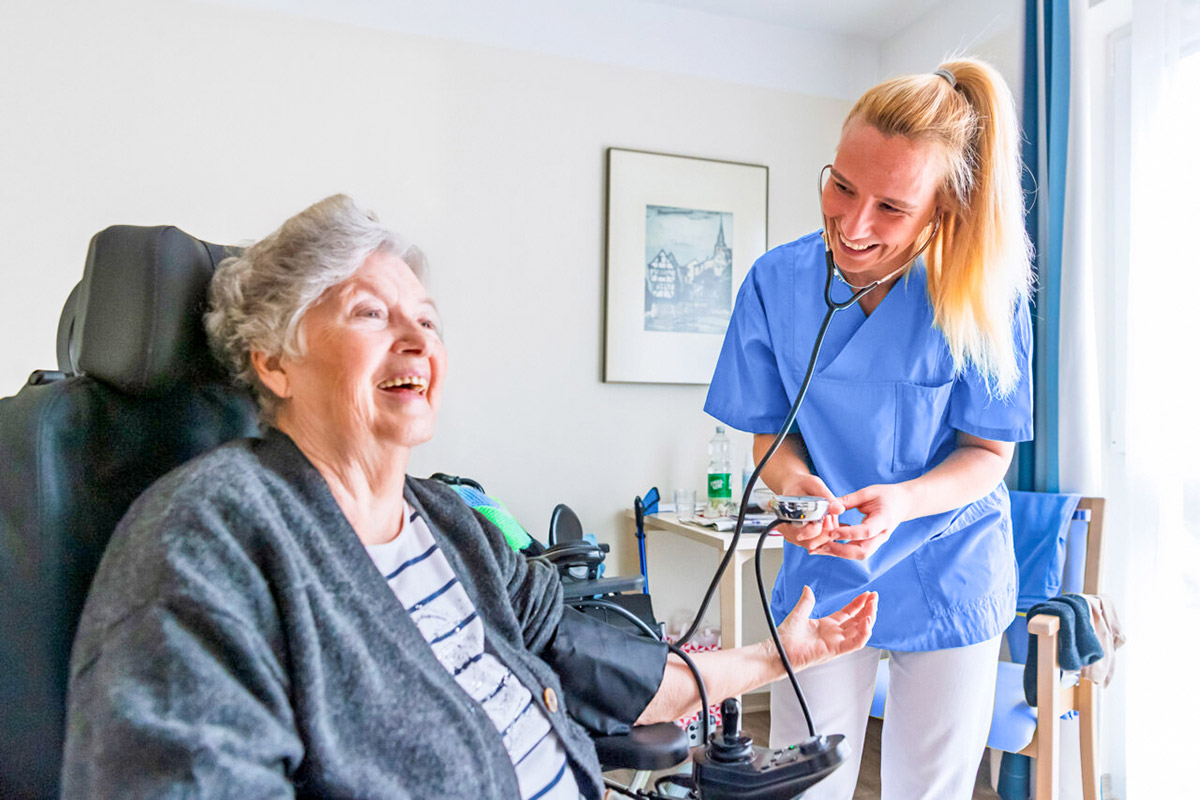 Eine Pflegerin misst den Blutdruck einer Bewohnerin.