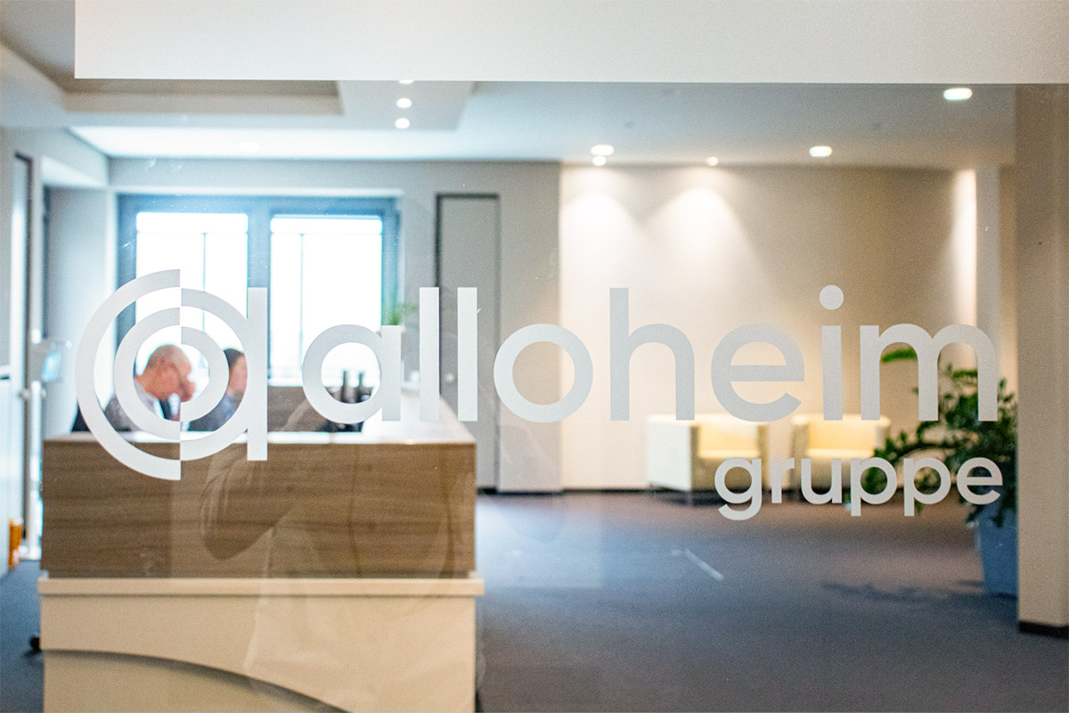 Alloheim Gruppe Logo auf Glastür mit Eingangsbereich