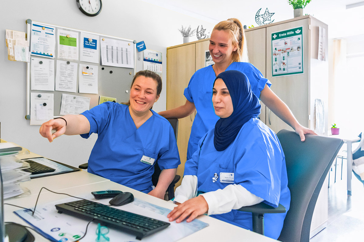 Drei Pflegerinnen schauen gemeinsam auf einen Computerbildschirm