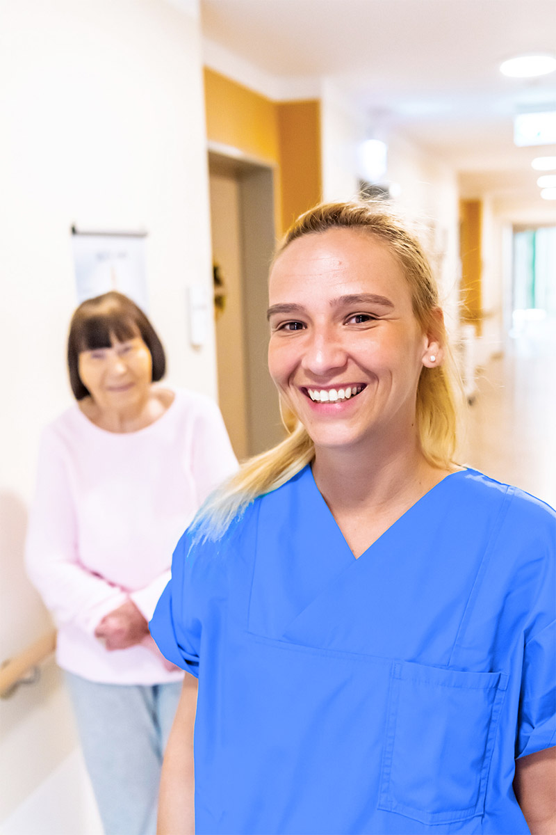 Bewohnerin und Pflegerin im Flur eines Alloheim Pflegeheims