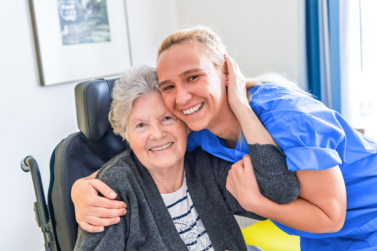 Pflegekraft legt den Arm um Bewohnerin